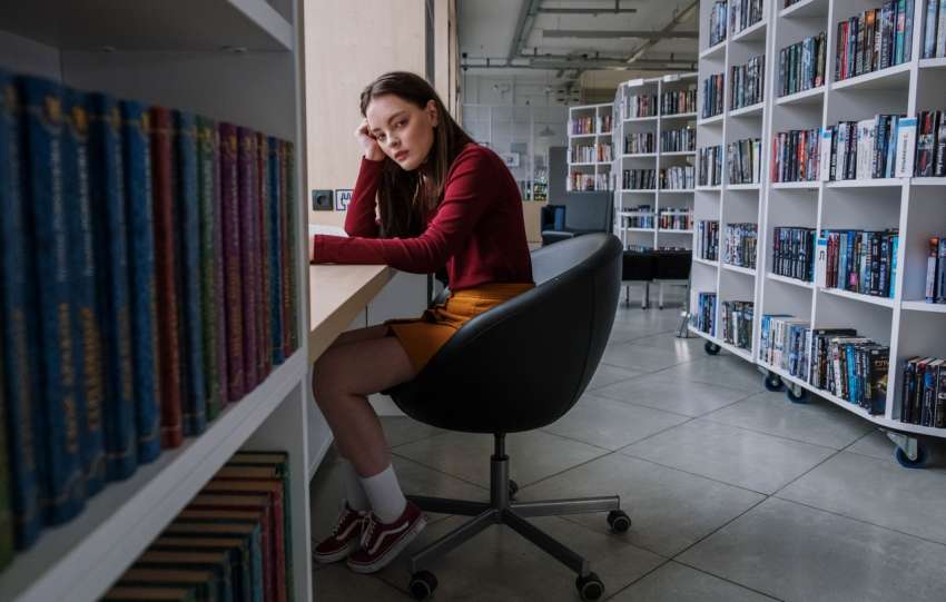 młoda dziewczyna siedzi w bibliotece
